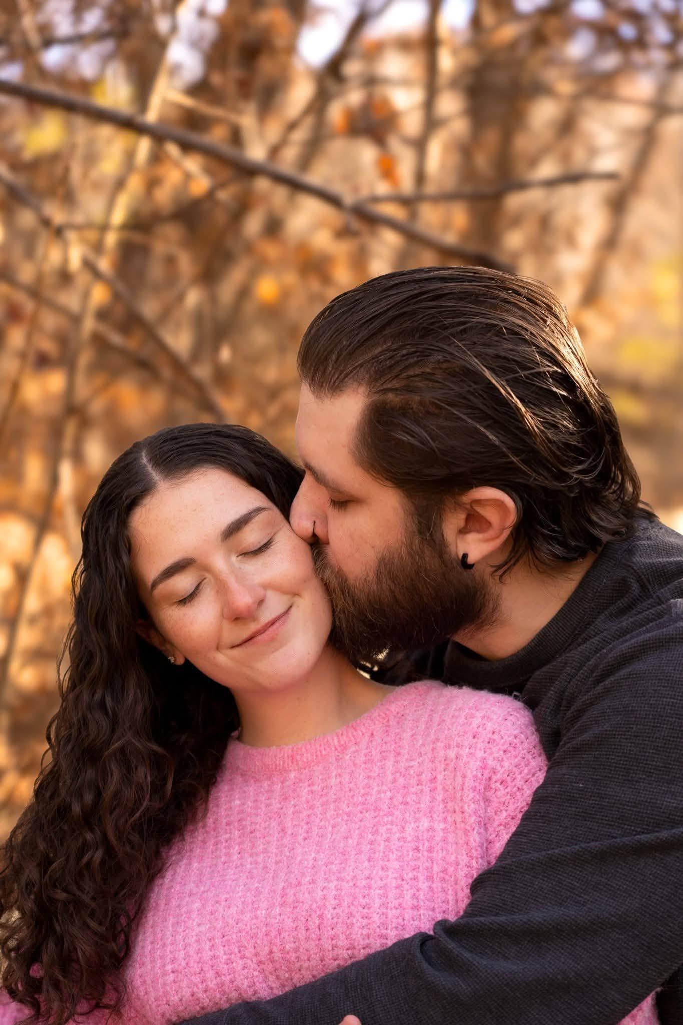 A couple embracing, one kissing the other on the cheek