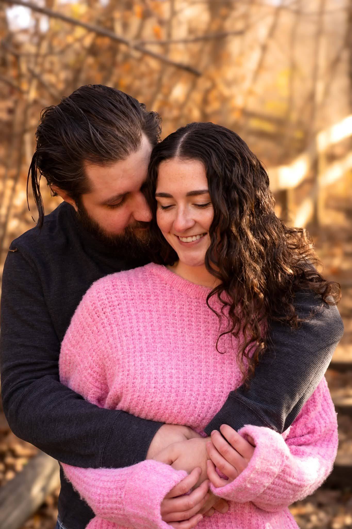 A couple holding each other closely among autumn leaves