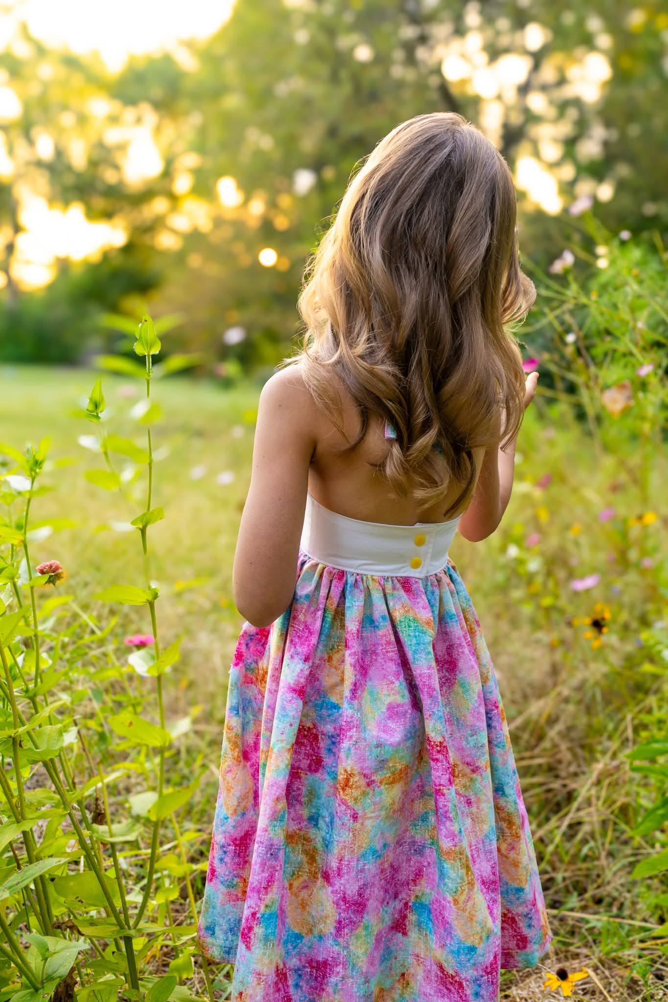 A girl seen from behind walking into a meadow of wildflowers