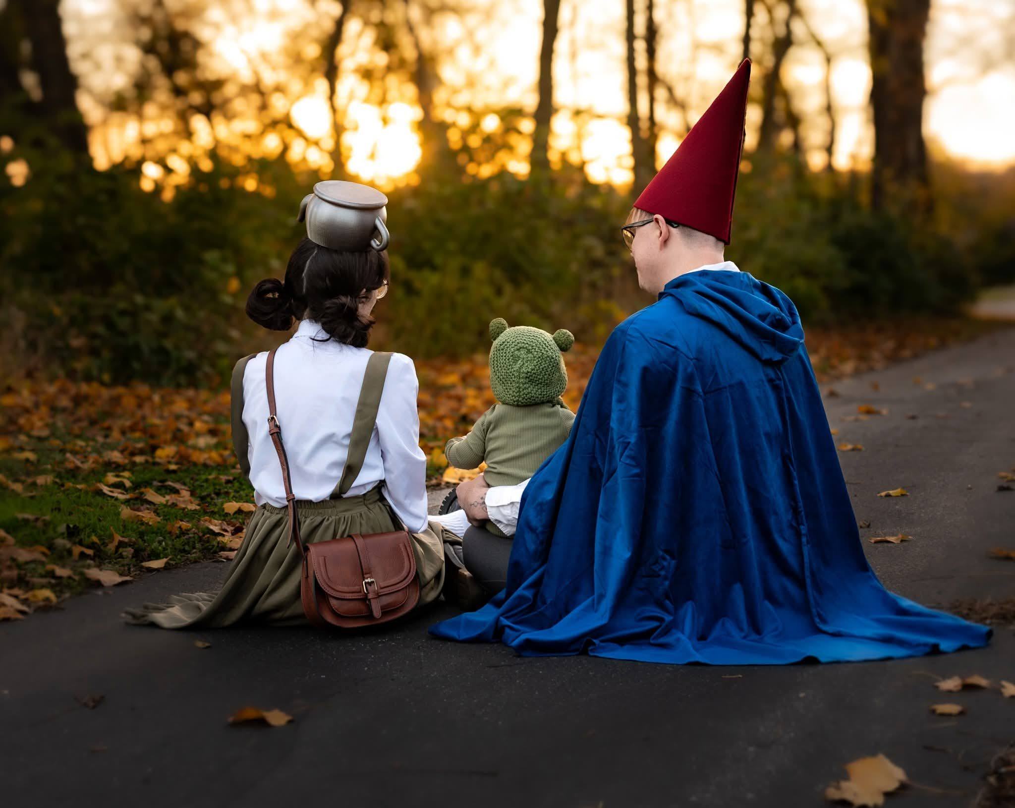 Two children in handmade costumes sitting on a road at sunset, backlit by golden light