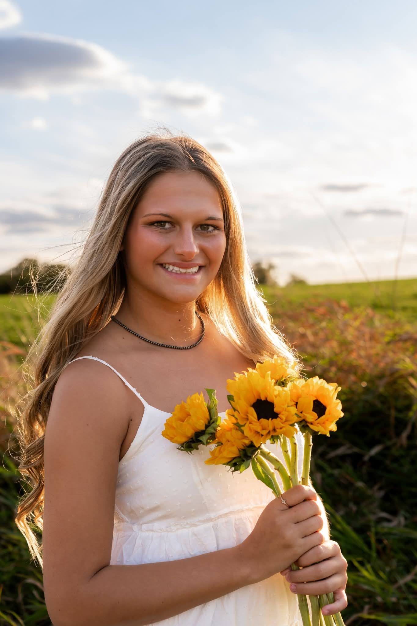 A senior holding sunflowers, smiling at the camera